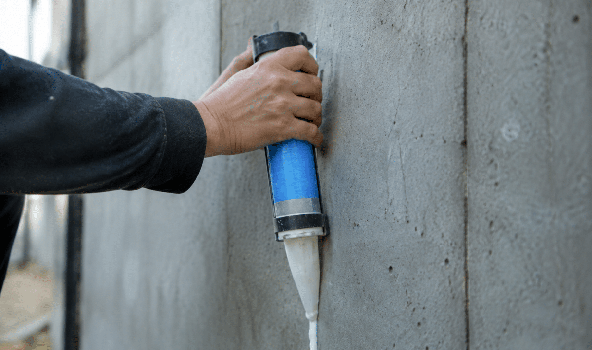 tube adhesif applique verticalement sur surface beton grise