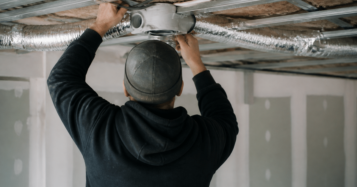 Personne installant conduit ventilation dans plafond interieur