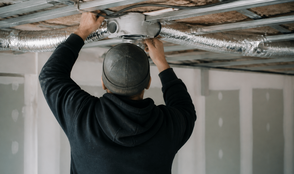 Personne installant conduit ventilation dans plafond interieur