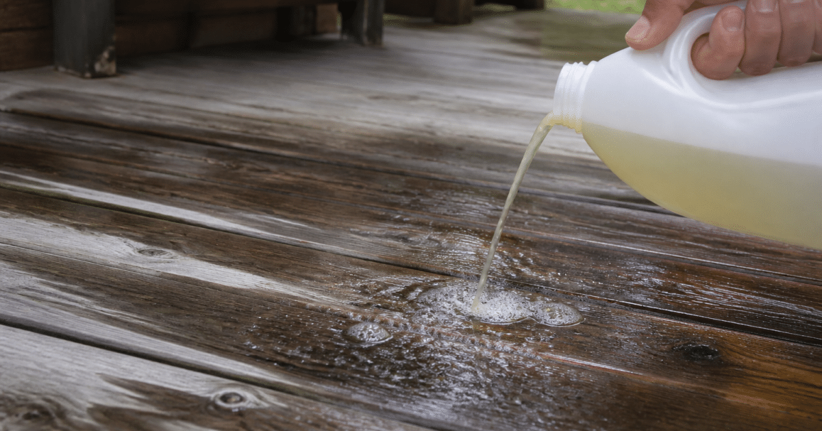 Bouteille de nettoyant versee sur planches bois mouillees