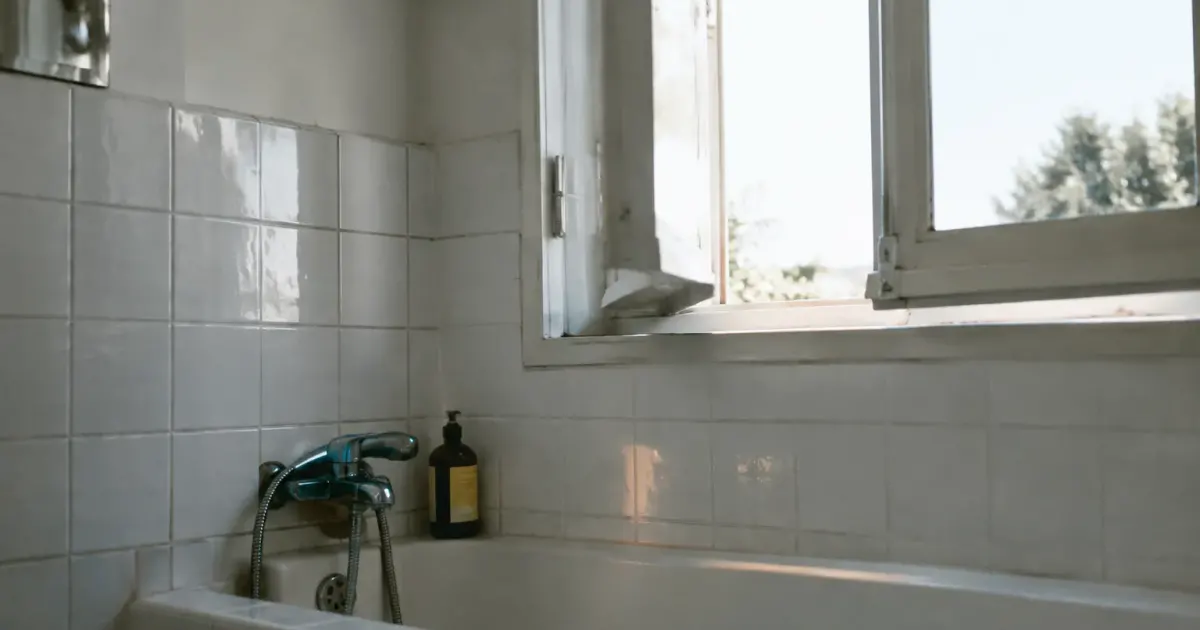 Fenetre entrouverte au dessus de la baignoire carrelee