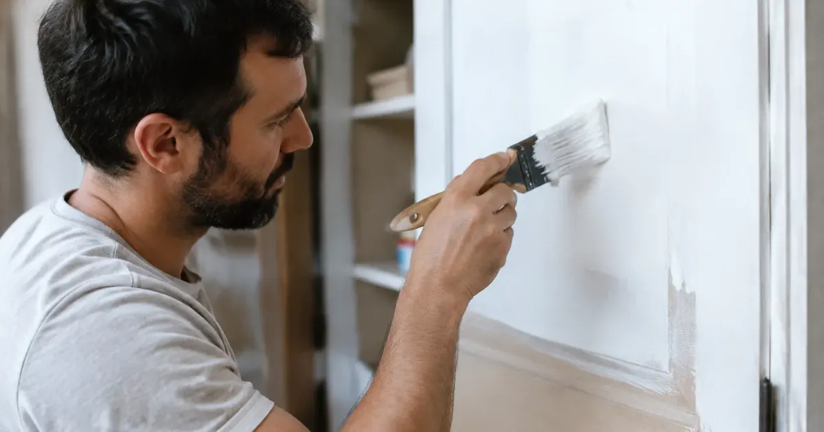 Ouvrier appliquant une couleur blanche sur une porte d'armoire